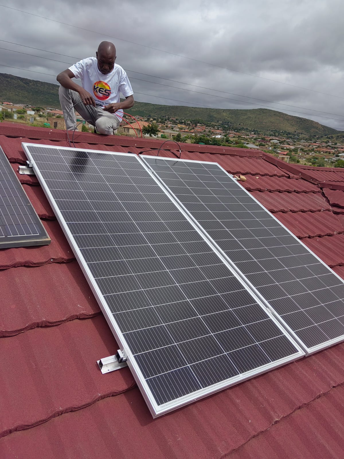 KES installer fitting solar panels for a community project
